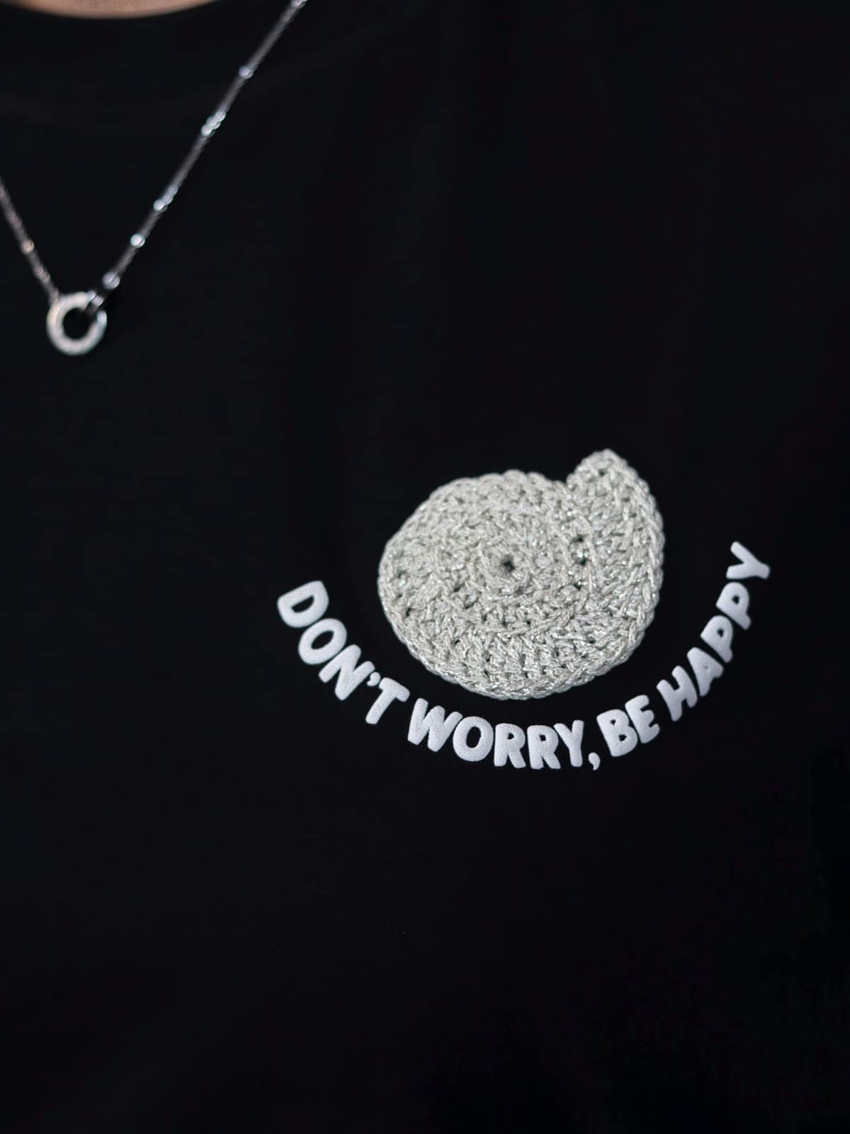 Primer plano del caracol tejido a mano en crochet sobre la camiseta negra