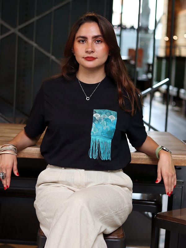 Camiseta negra con bolsillo de brocado de conchas turquesa y flecos turquesa