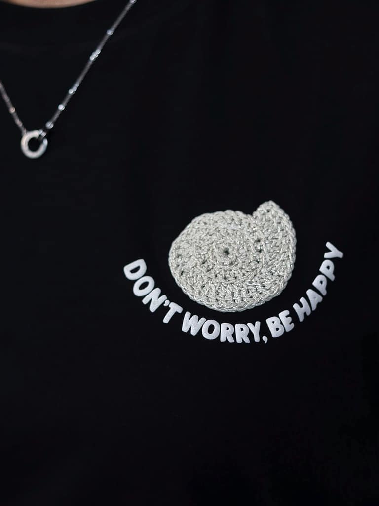 Primer plano del caracol tejido a mano en crochet sobre la camiseta negra